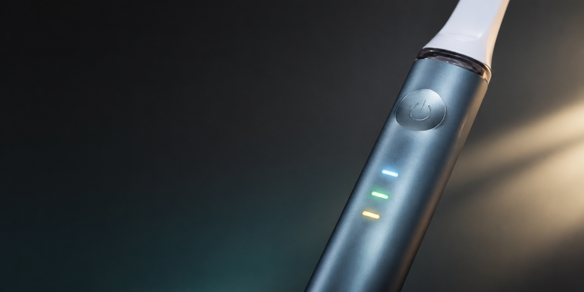 Close-up of AeroBrush Pro handle showing three glowing LED mode indicator lights